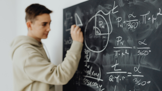 Boy writing equations on chalkboard